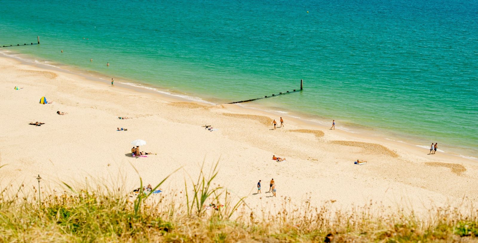 Visitors relaxing on southbournes golden beach next to blue sea 